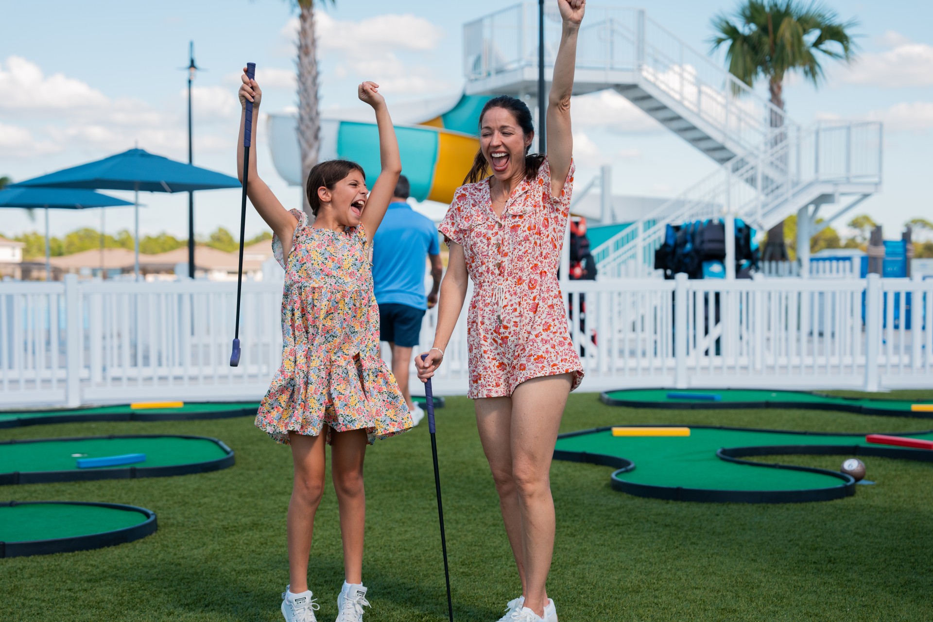 a woman and a girl holding golf clubs