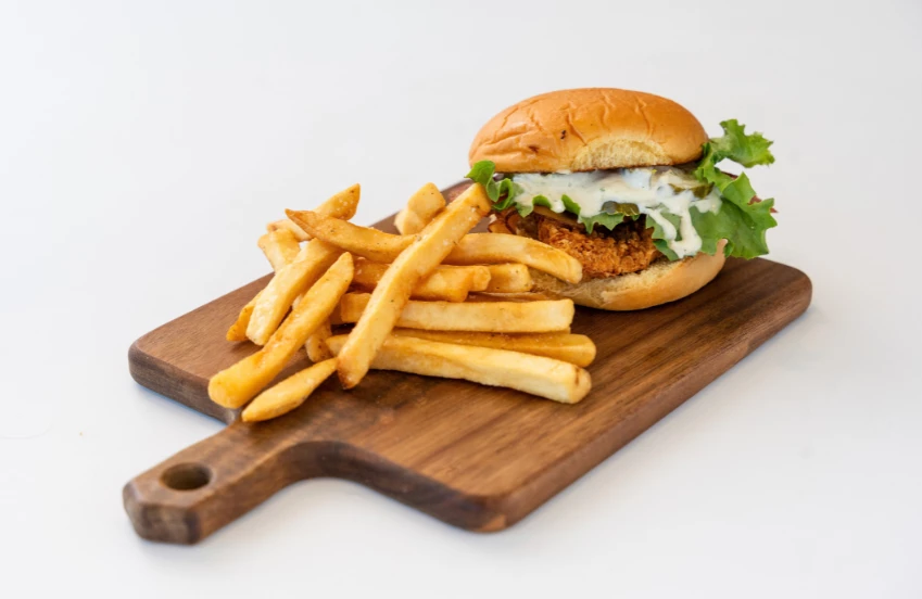a burger and fries on a wooden board