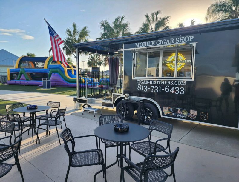 a black mobile cigar shop with a slide and a slide in the background