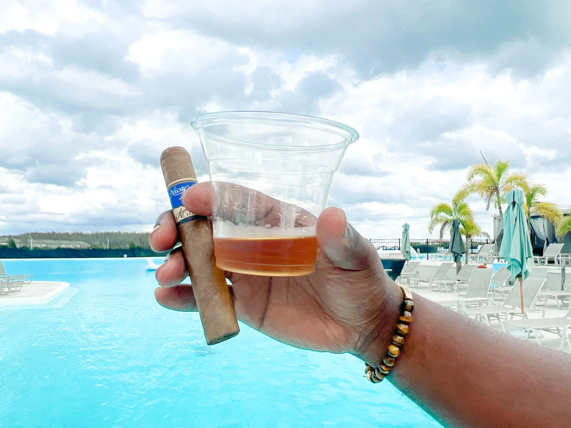 a hand holding a cigar and a glass of liquid