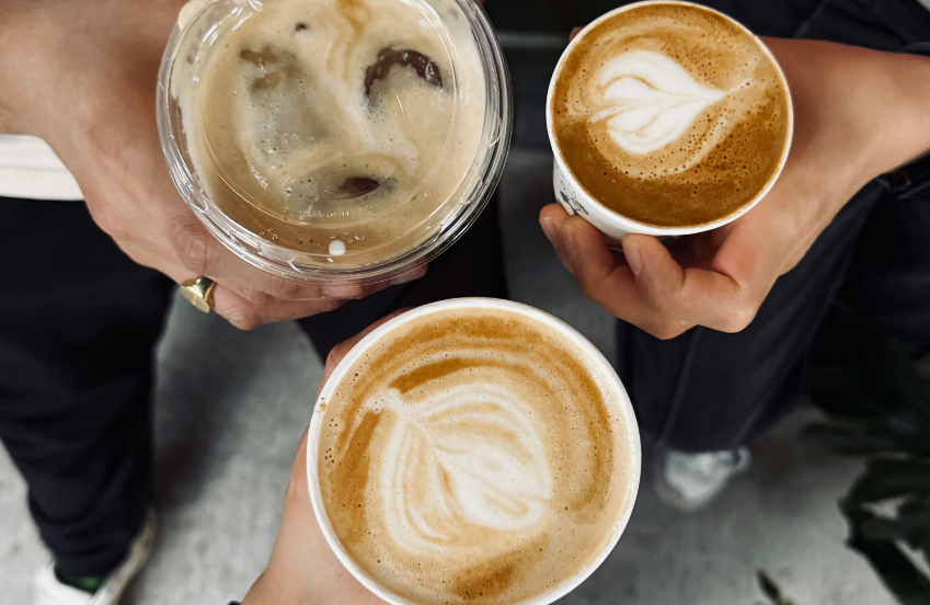 a group of hands holding cups of coffee