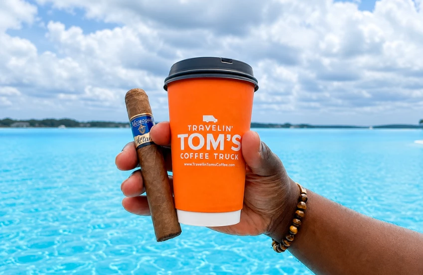 a hand holding a cup and a cigar