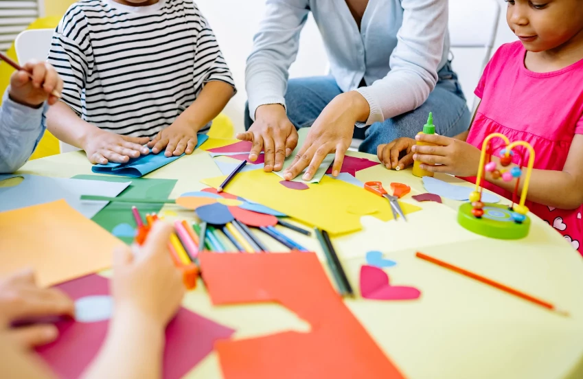 a group of people sitting around a table with paper and scissors