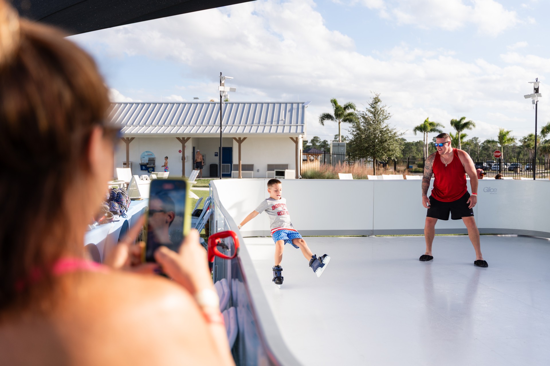 a boy on skates on a white surface with someone taking a picture of him
