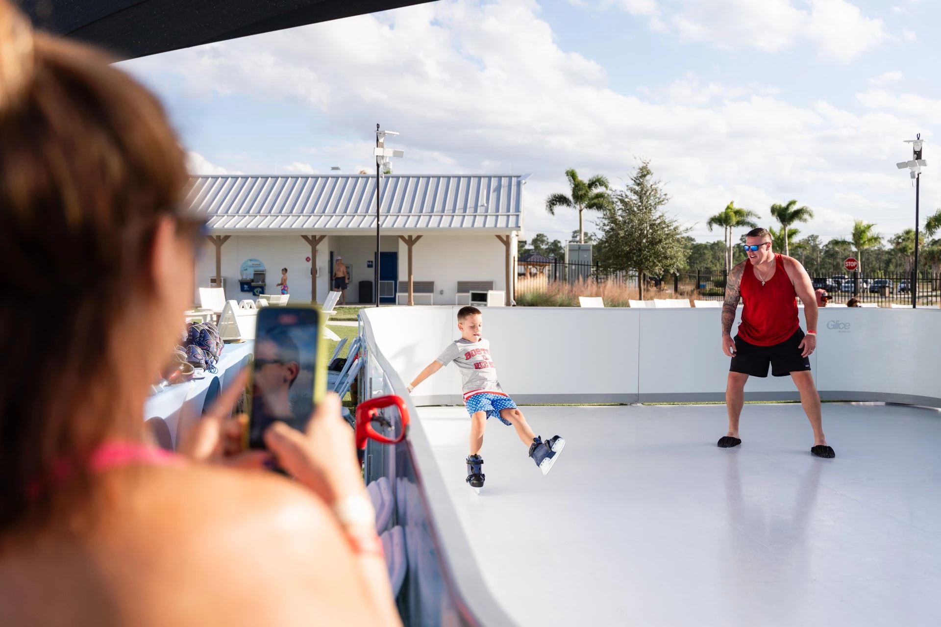 a boy on skates on a white surface with someone taking a picture of him