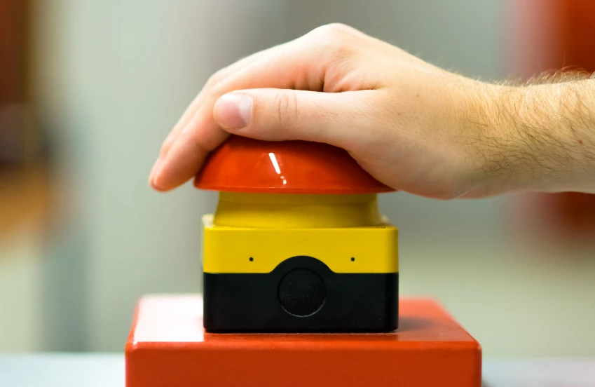 a hand on a red and yellow button