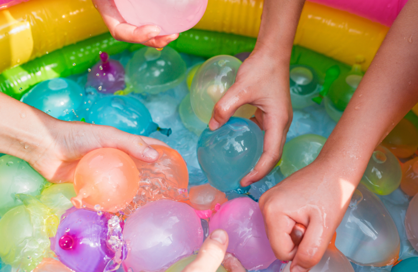 a group of hands holding colorful balls in a pool