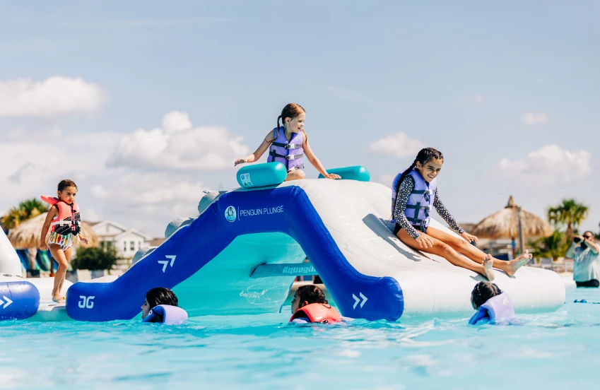 a group of kids on a floating slide in a pool