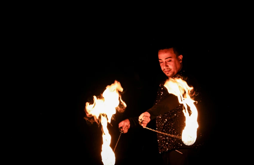 a man holding fire juggling sticks