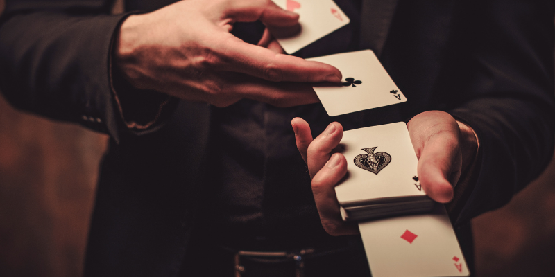 a person's hands holding playing cards