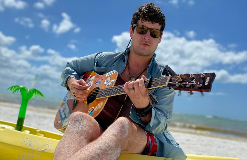 a man sitting on a yellow boat playing a guitar