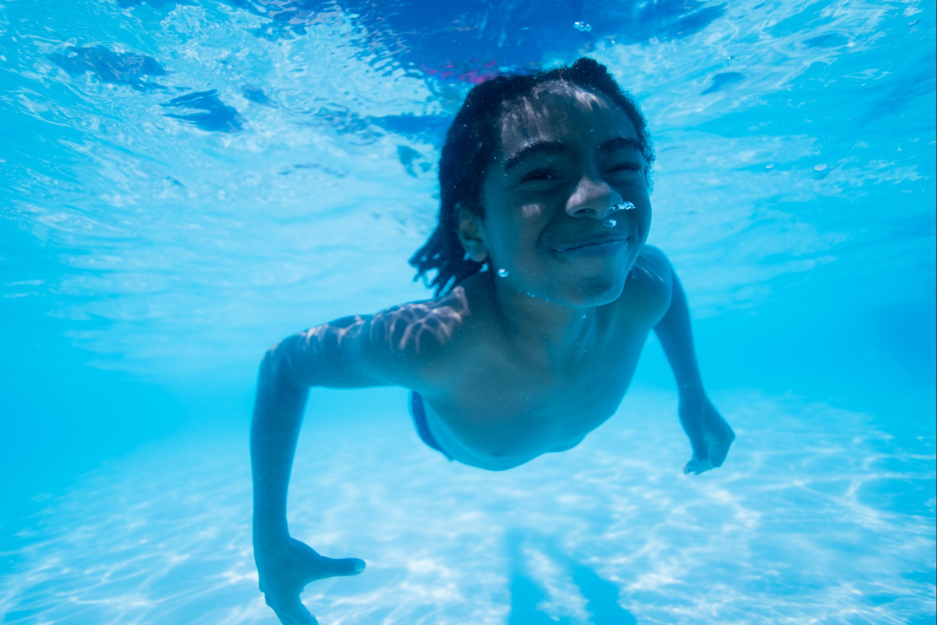 a boy swimming underwater in a pool