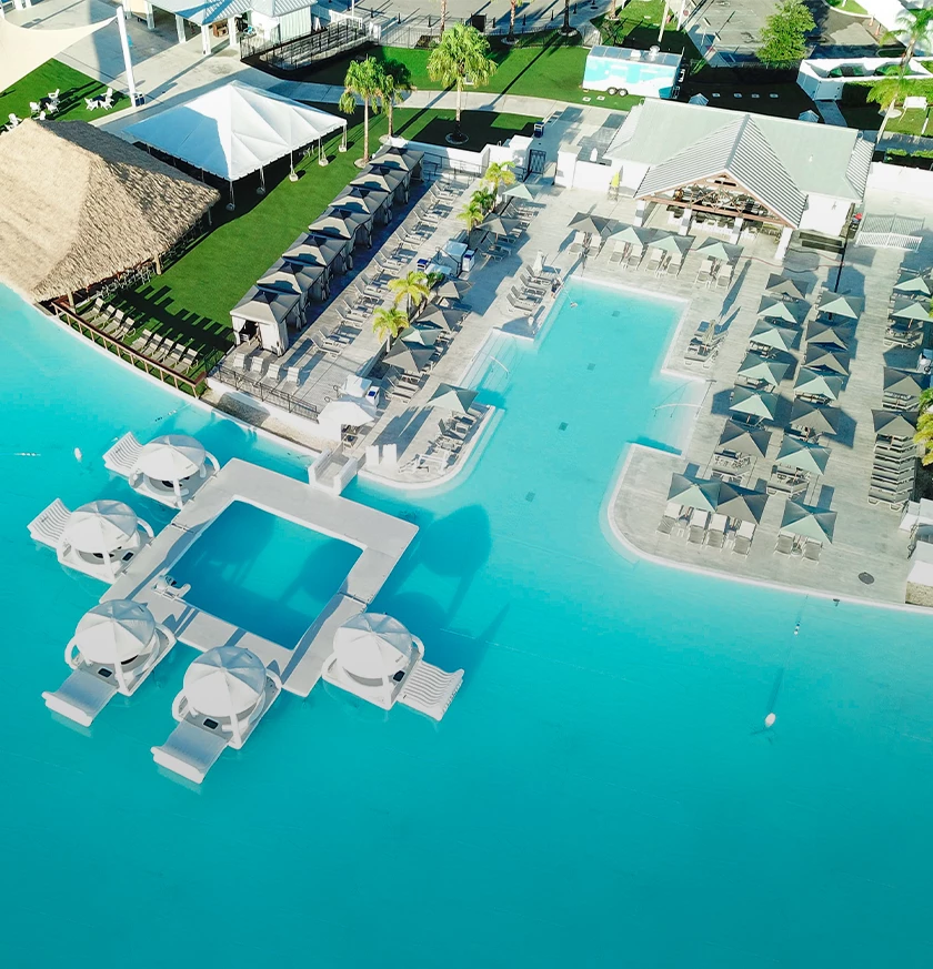 a pool with umbrellas and chairs and a building with grass and trees