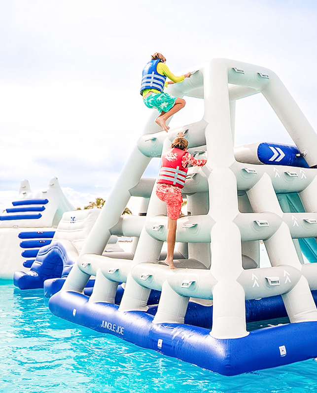 a couple of people climbing up a floating structure in a pool