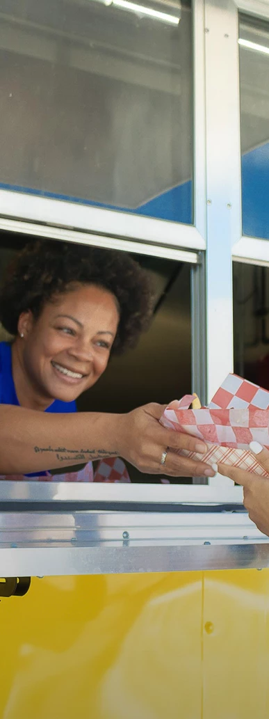 a woman smiling at a woman holding a paper bag