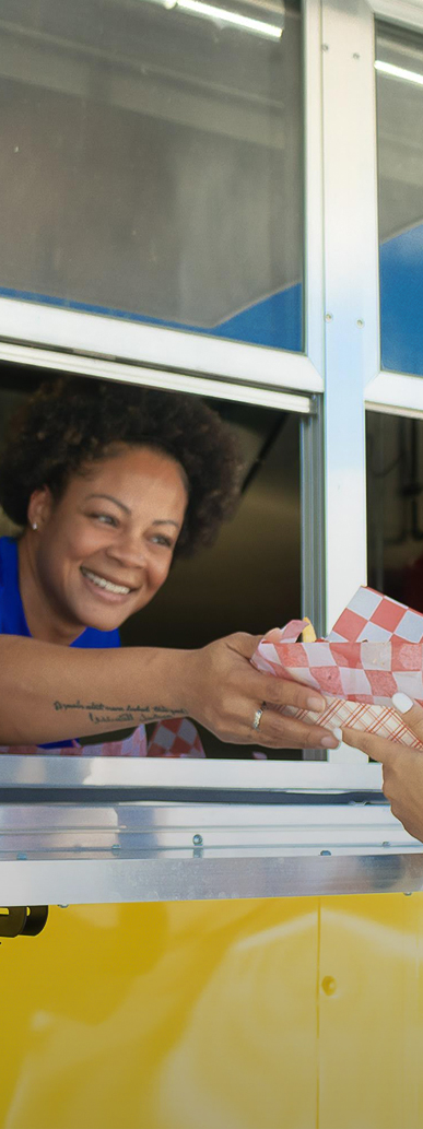 a woman smiling at a woman holding a paper bag
