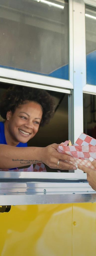 a woman smiling at a woman holding a paper bag