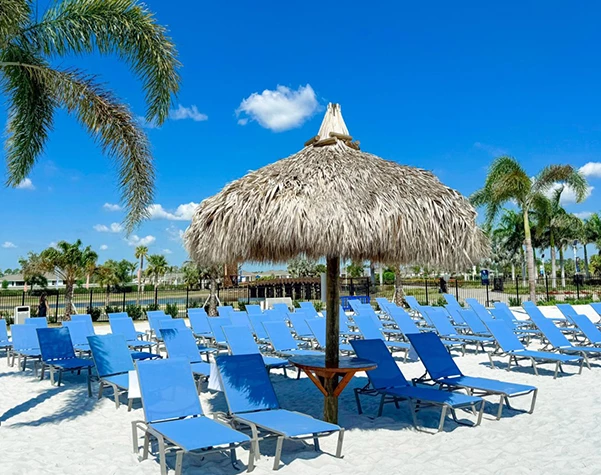a group of blue chairs and a straw umbrella on a beach