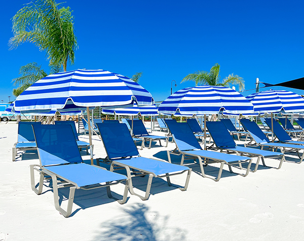 a group of blue and white striped umbrellas and lounge chairs on a beach