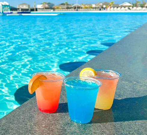 a group of drinks on a ledge by a pool