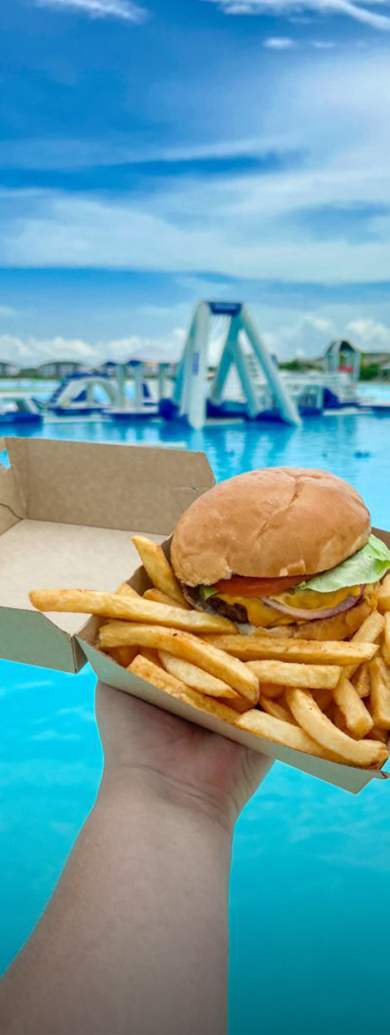 a burger and fries in a box by a pool