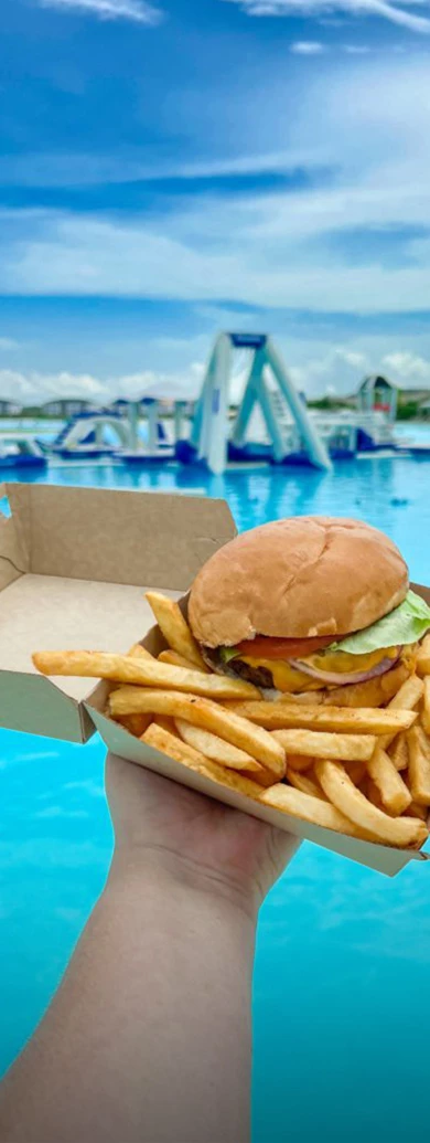 a burger and fries in a box by a pool