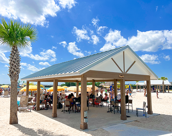 a group of people sitting under a covered area on a beach