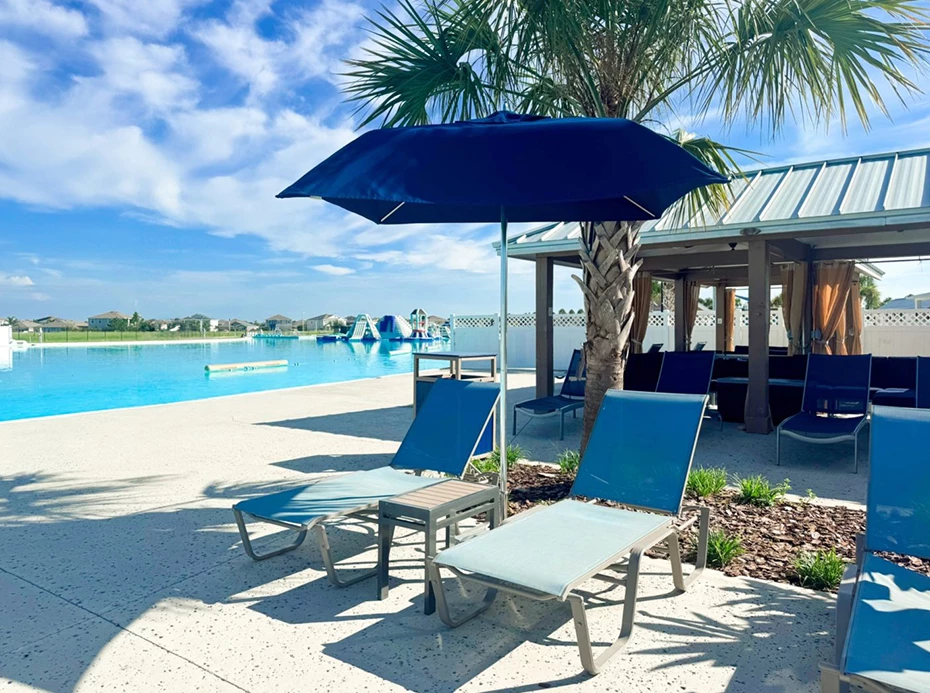 a pool with a blue umbrella and lounge chairs