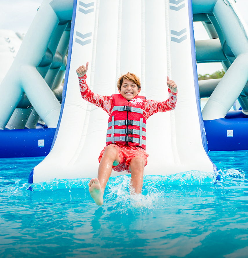 a boy in a life jacket jumping into a water slide