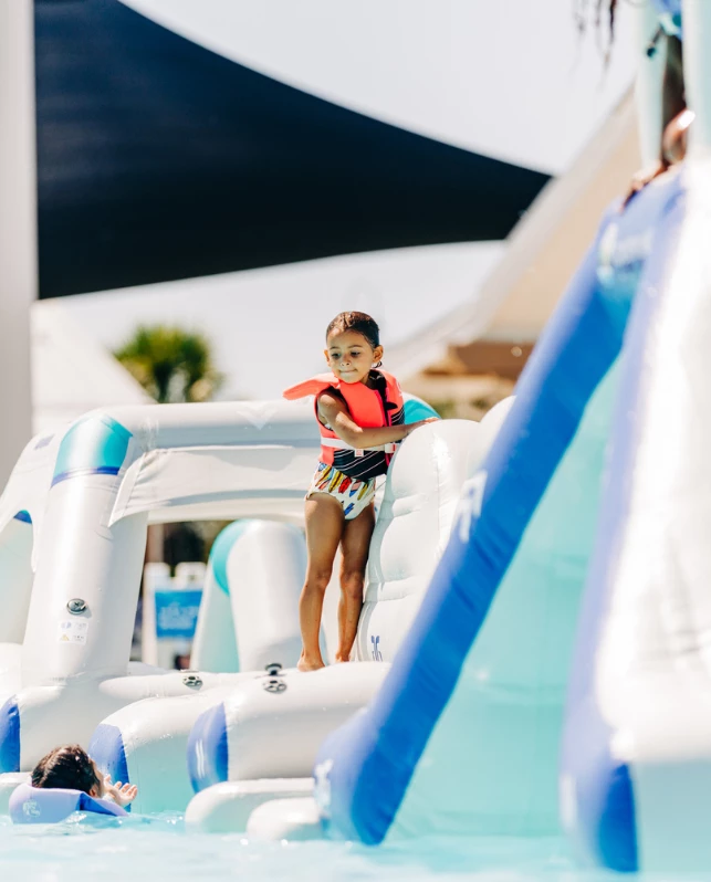 a girl in a life jacket on a floating slide