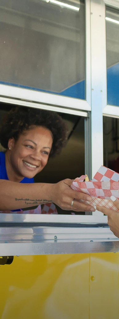 a woman smiling at a woman holding a paper bag