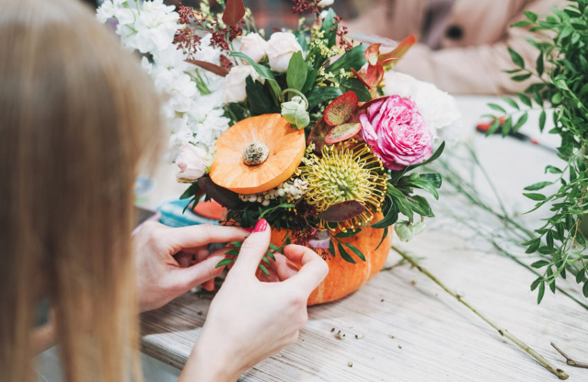 a person arranging flowers in a pumpkin
