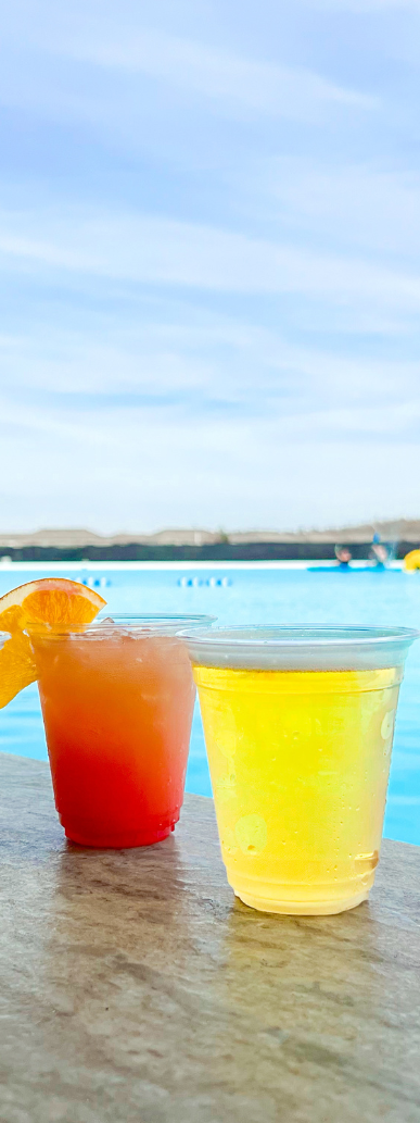 two drinks on a table by a pool