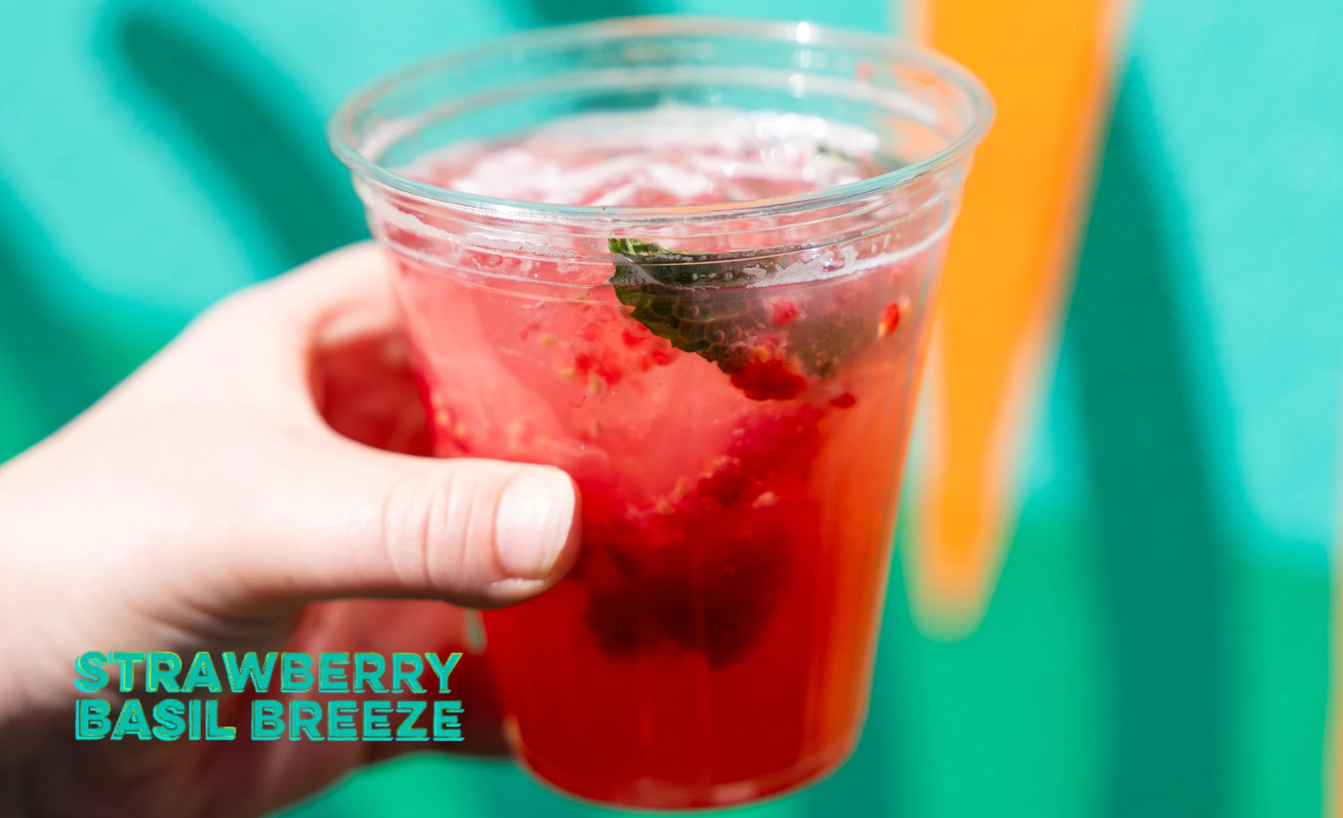a hand holding a plastic cup of red liquid