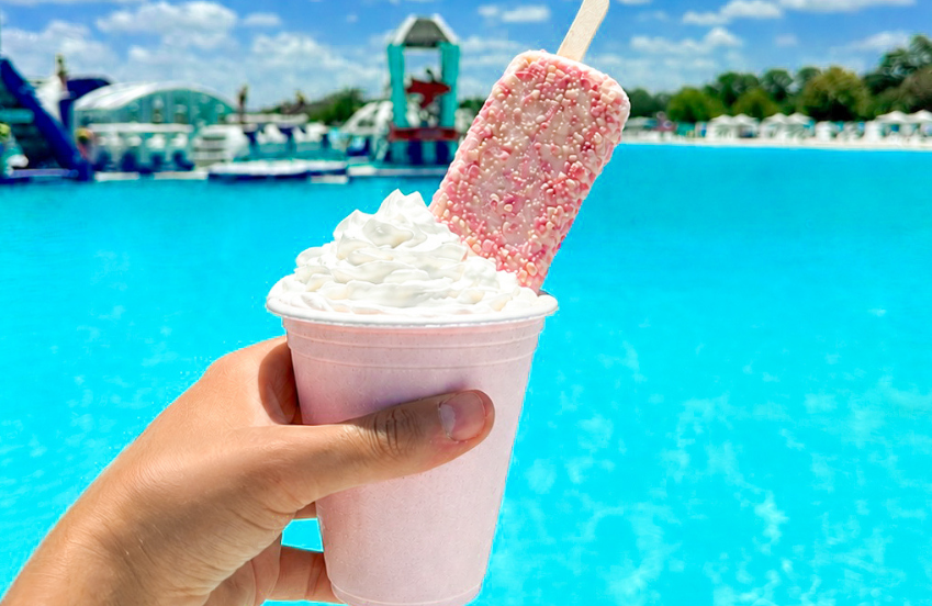 a hand holding a cup of ice cream and a popsicle