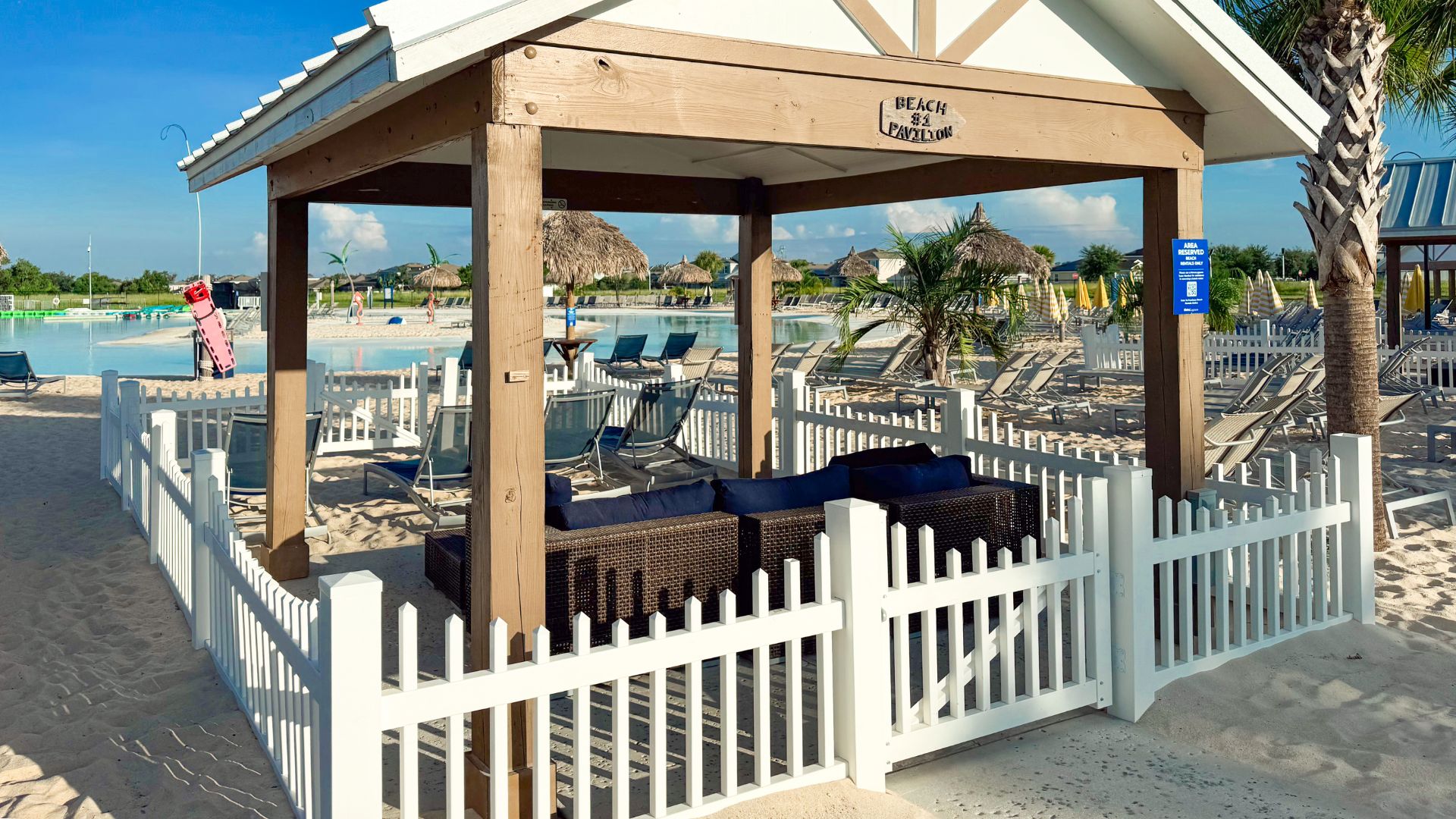 a white fence and a white fence with a white fence and a beach with chairs