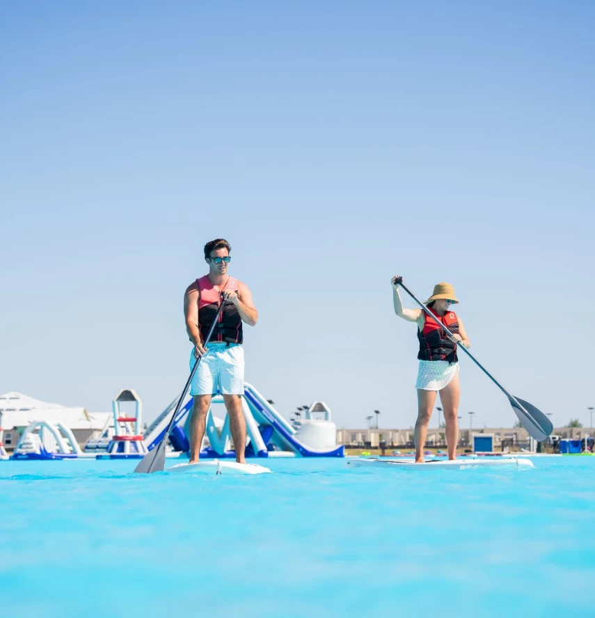 a man and woman on paddle boards in a pool