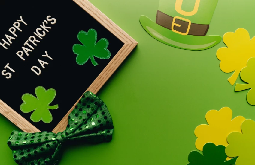 a black board with a bow tie and shamrocks on a green background