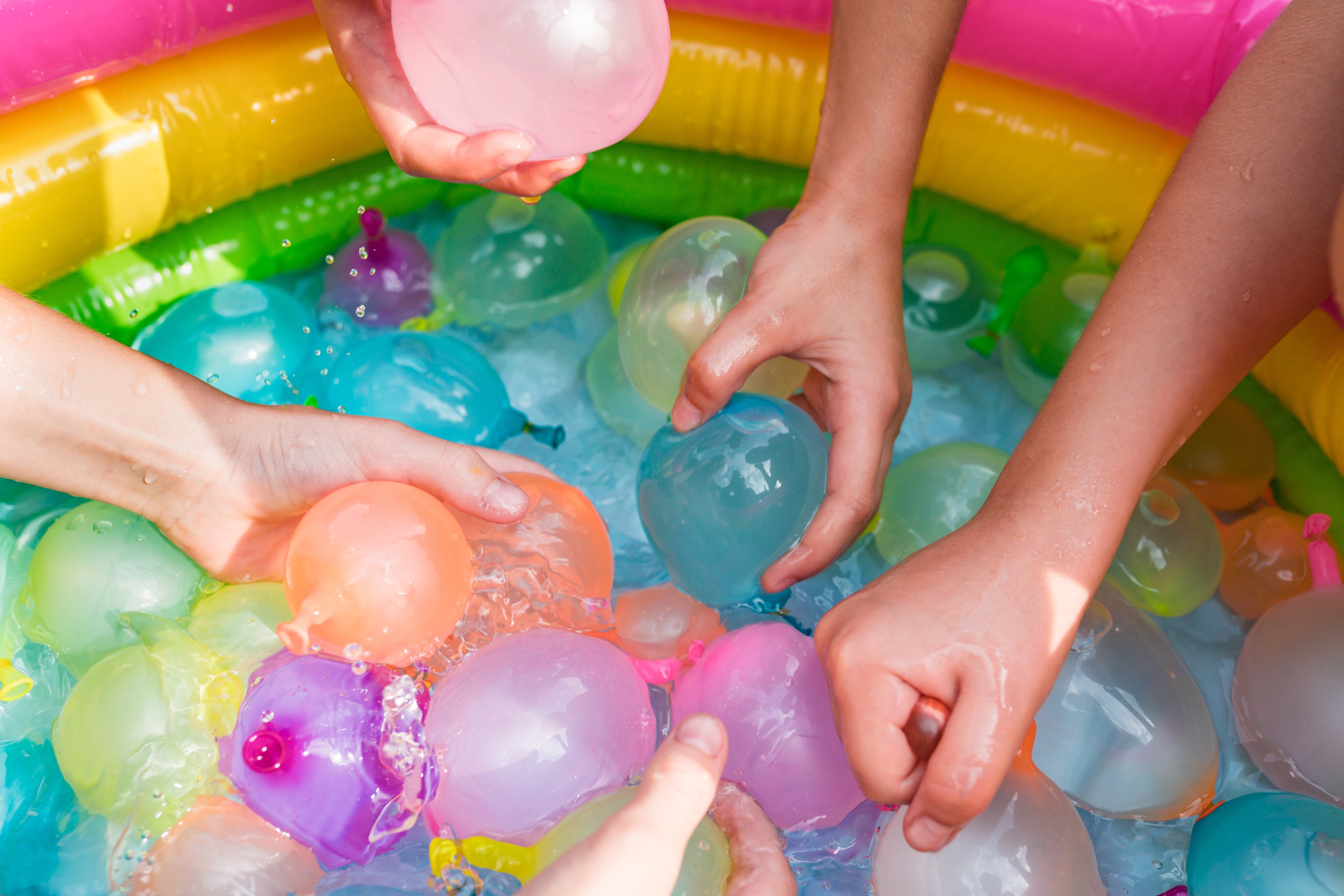 hands holding a colorful ball in a pool