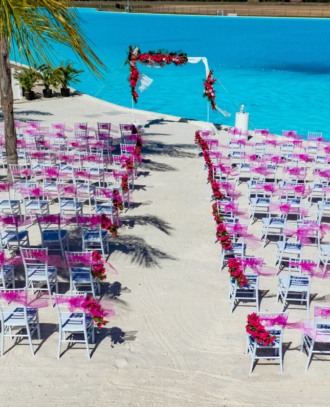 chairs on a beach with a large arch and flowers