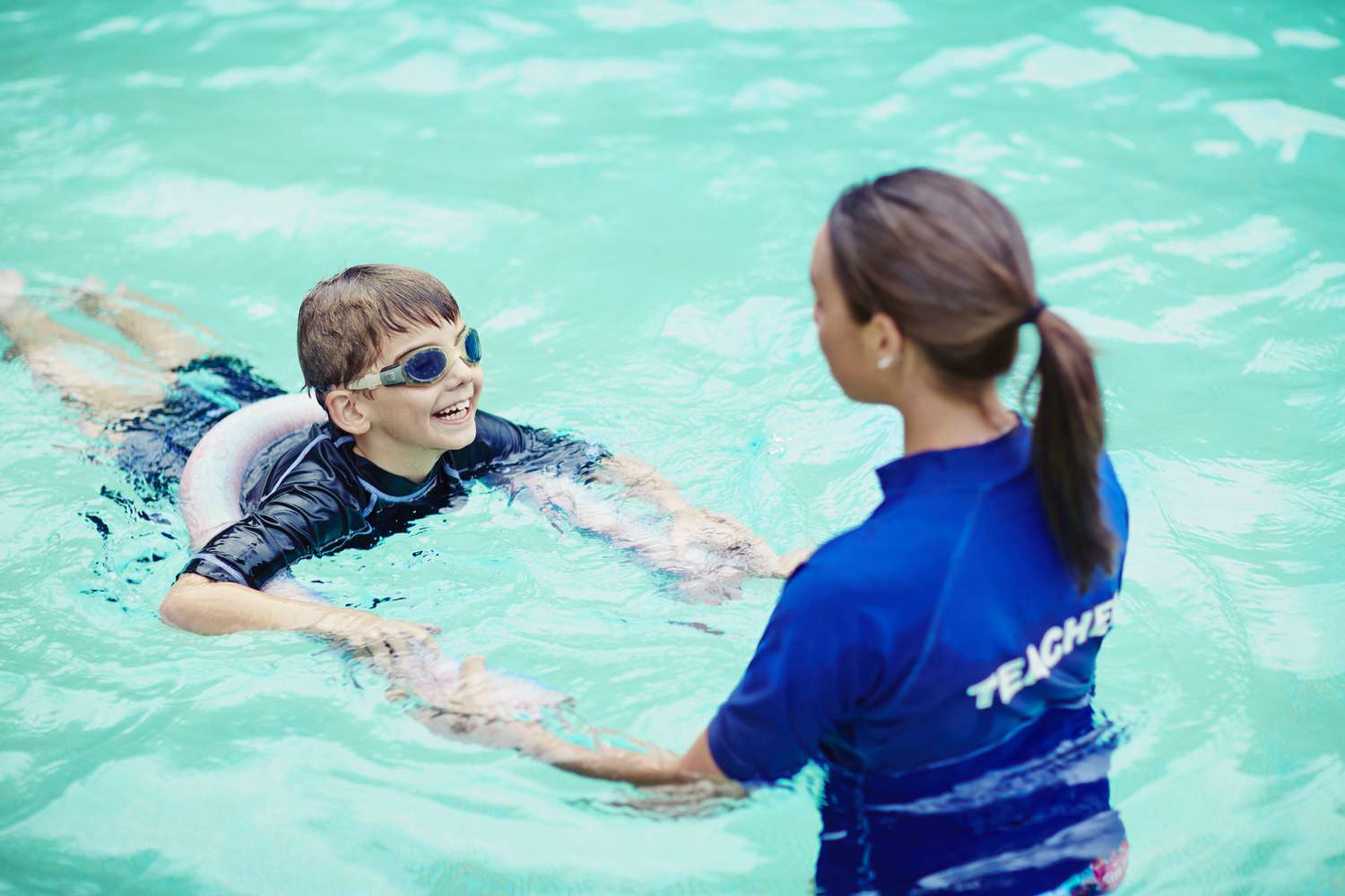 a boy in a pool with a teacher