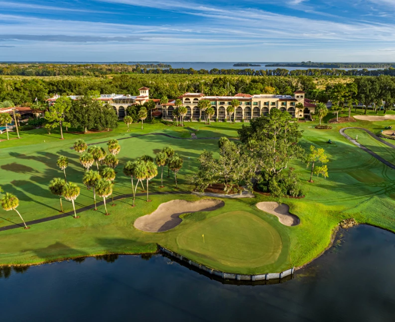 a golf course with a building and a body of water