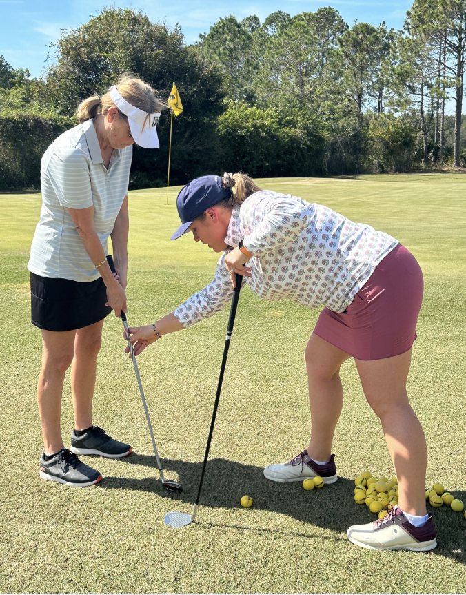 a woman holding a golf club and putting on a golf course