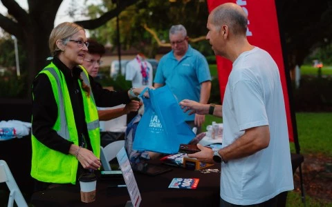 a man handing a blue bag to a woman