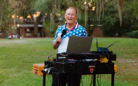 a man standing in a grass field holding a microphone