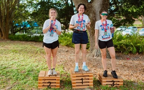 a group of women standing on wooden boxes with medals
