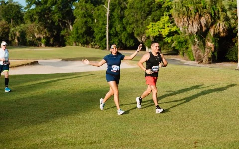a man and woman running on a grass field