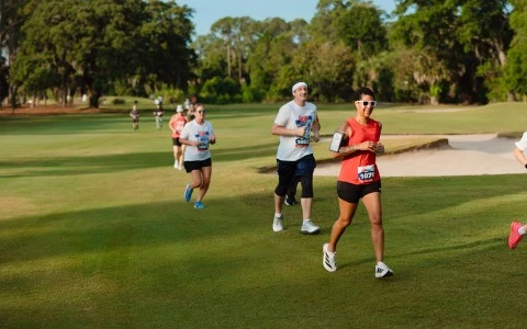 a group of people running on a grass field