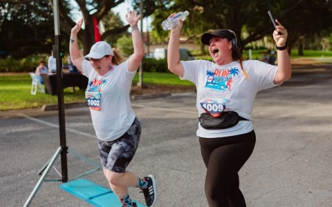 two women running with their arms up and their arms raised