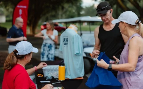 a man holding a blue bag and a woman standing next to a table with a person on it